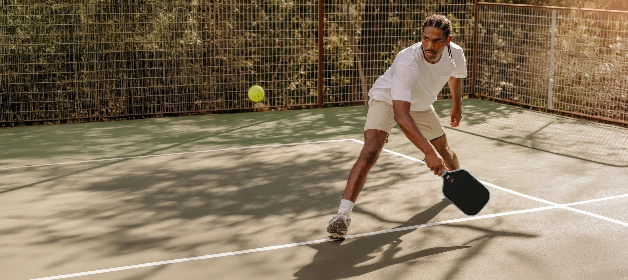 Man playing jojolemon paddleball on a court with a ball in the court